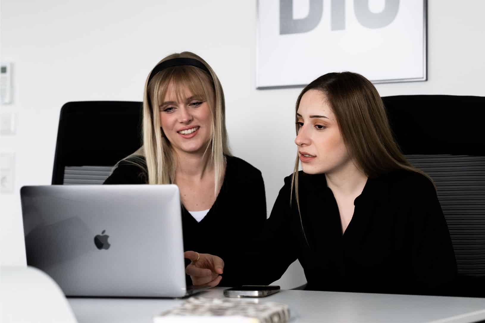 Teaching Finance Mitarbeiterinnen zusammen vor einem Macbook